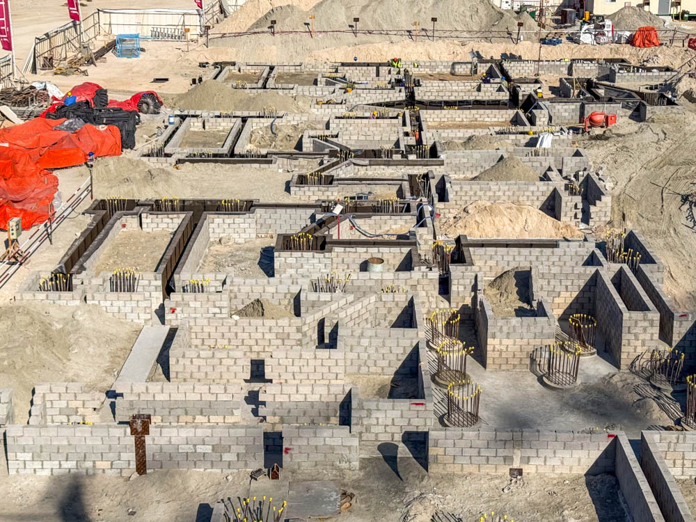 Cotier House 2 By Imtiaz An aerial view of a construction site featuring cinder block foundations and construction materials scattered throughout.